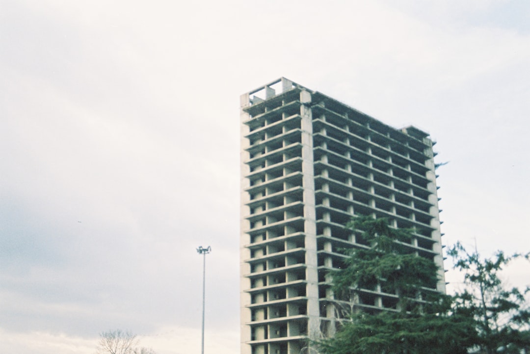 Modern dark building with trees and white base.